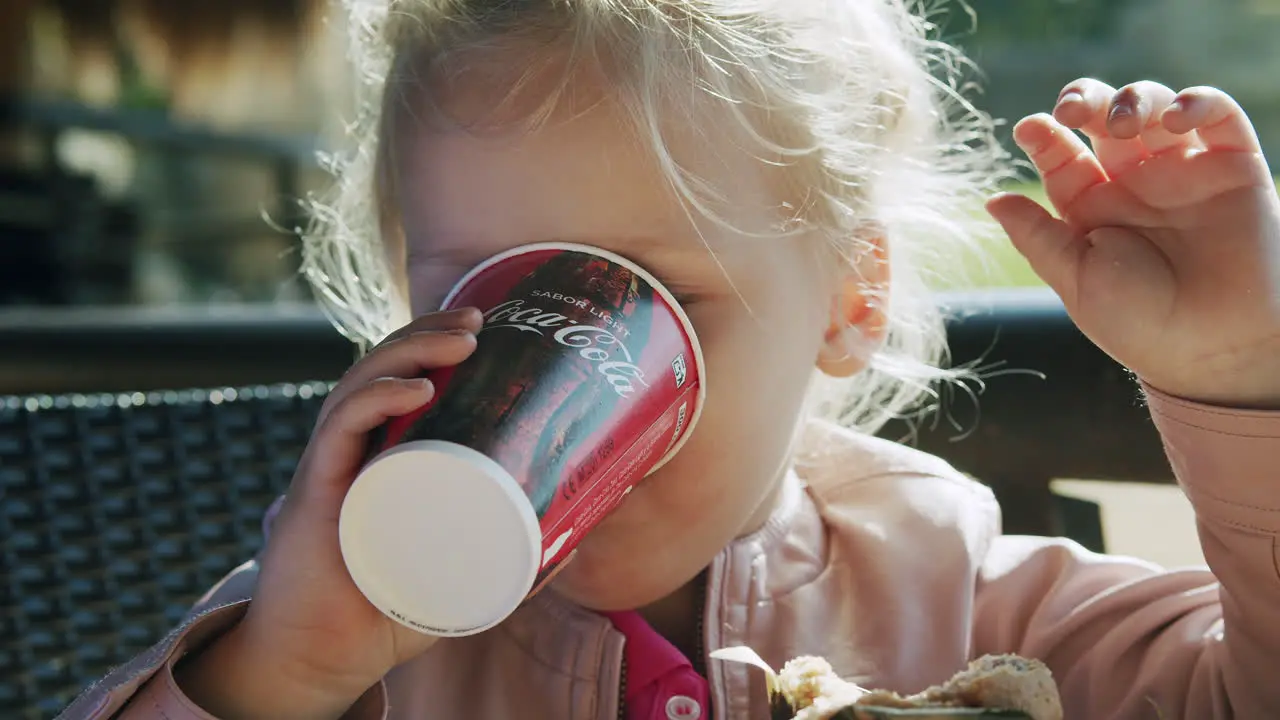 Little child finishing lunch with a cup of Coca Cola