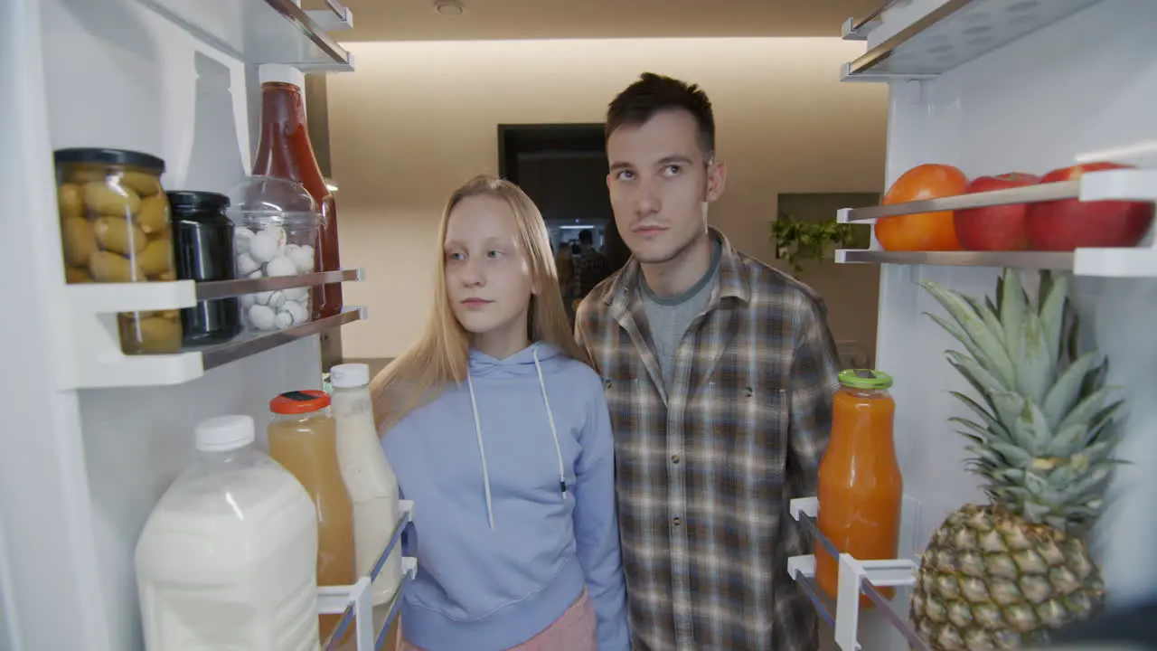 Hungry teenagers look inside the refrigerator