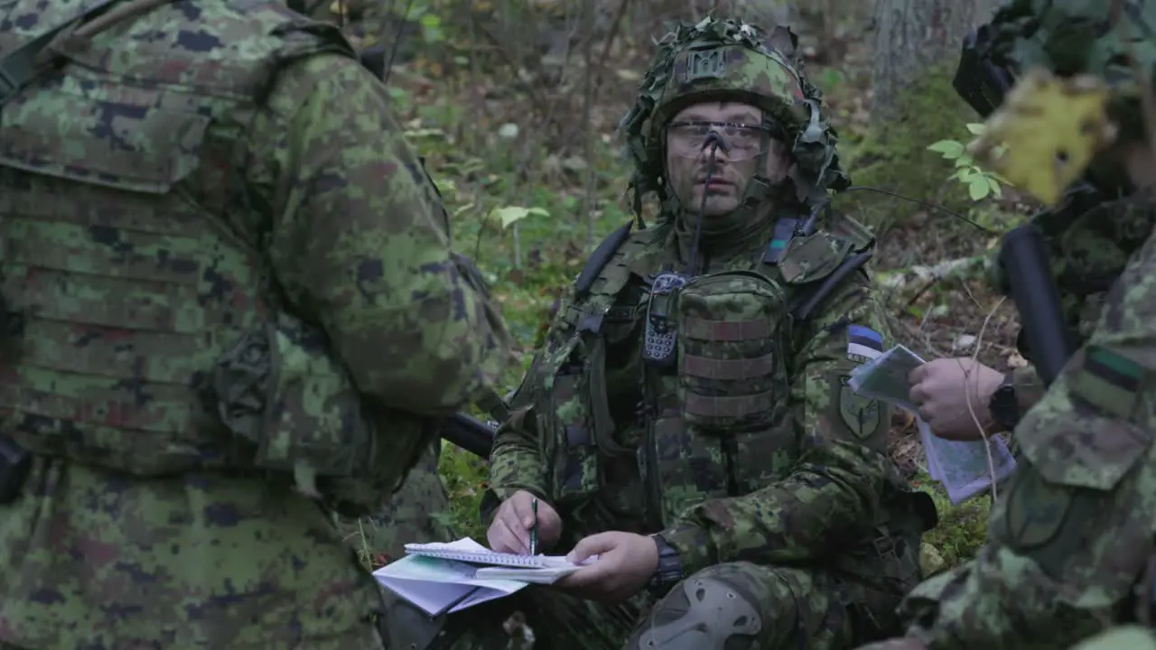 Soldiers in camouflage planning strategy in the forest wide shot handheld slow motion