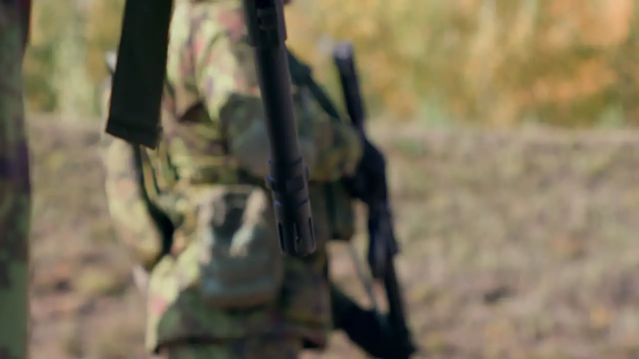 Rifle barrel foreground soldier holding a rifle in the background slow motion