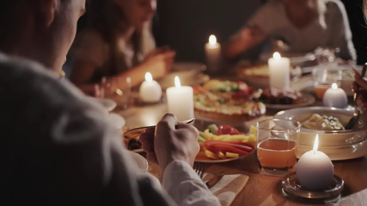 A large friendly family eats at the festive table by candlelight