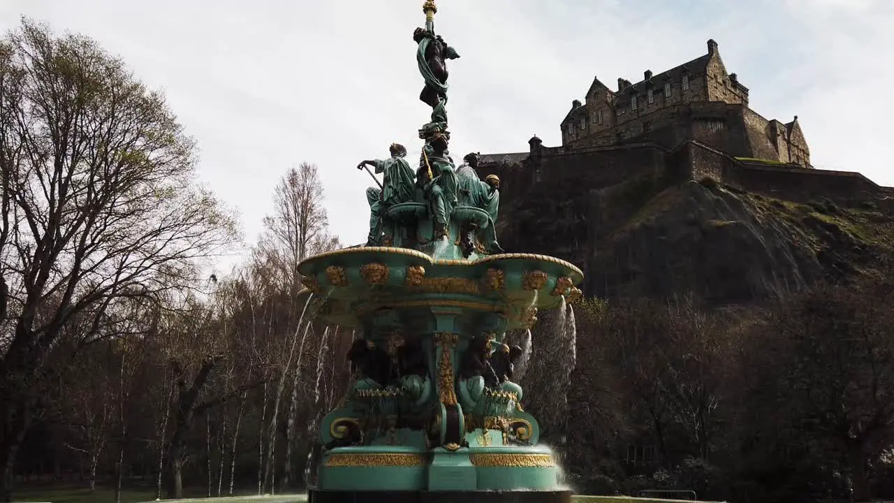 Fountain in Princes Street Gardens with water flowing and Edinburgh famous castle in the background