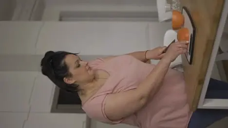 Attractive overweight woman preparing healthy meal cutting grapefruit closeup