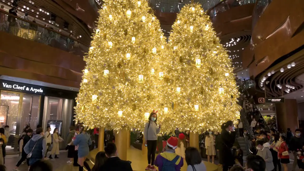 People celebrate the Christmas holidays as they pose for photos in front of a golden Christmas tree at a shopping mall in Hong Kong