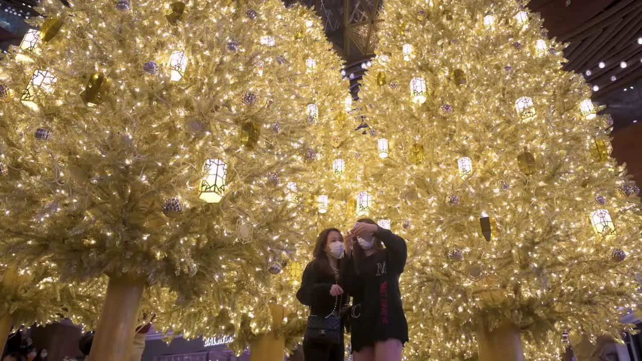 Women celebrate the Christmas holidays as they take a selfie in front of a golden Christmas tree at a shopping mall in Hong Kong