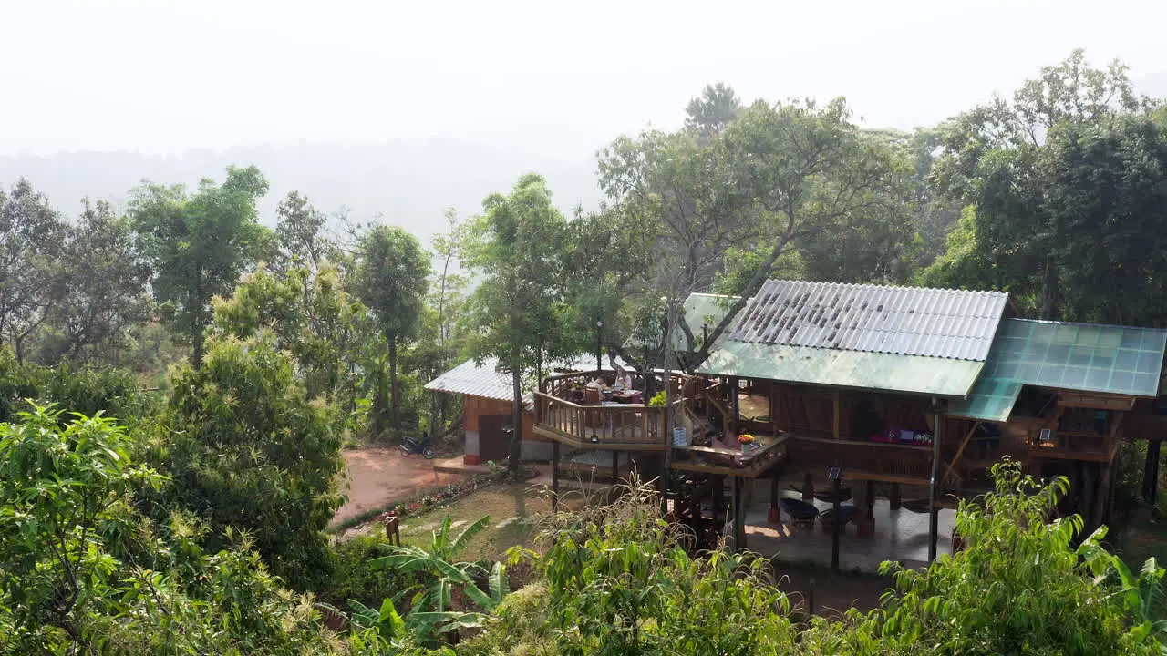 Couple having breakfast on treehouse terrace above exotic countryside