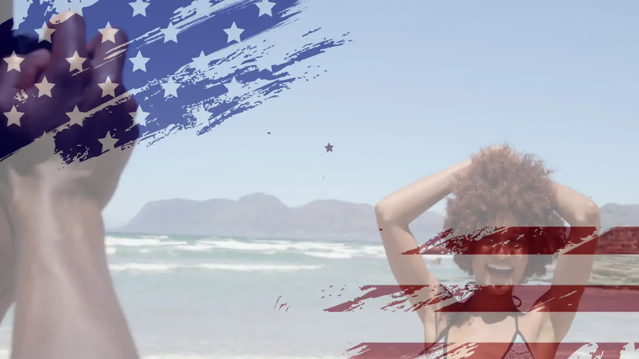 Animation of usa flag design against african american man taking pictures of his wife at the beach