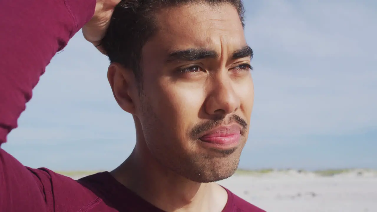 Portrait oh relaxed hispanic man standing in sun and wind on beach