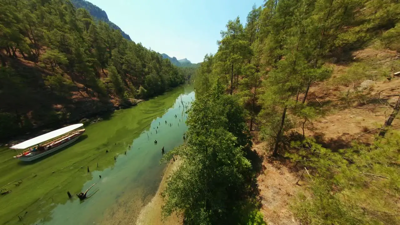 Aerial view drone flying on top of green mossy lake surrounded by trees and big rocks