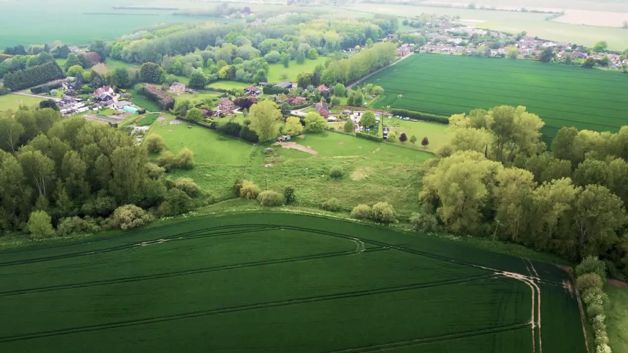 Flying over green fields towards a small village