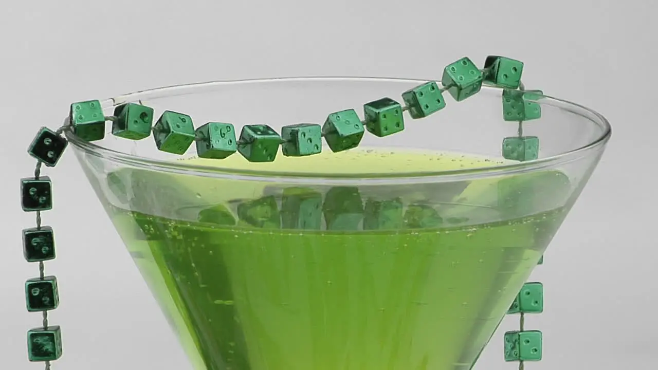 Beads of green dice adorn a cocktail glass