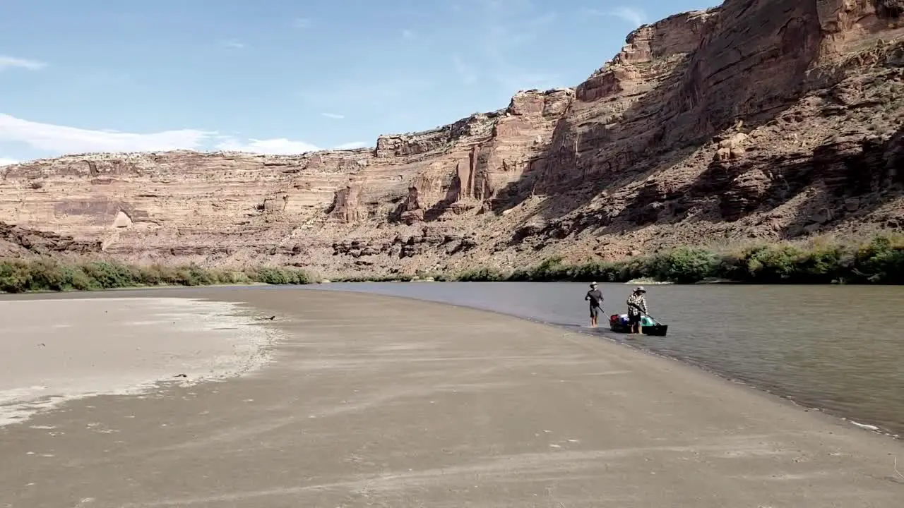 2 guys walking canoe down river in Utah