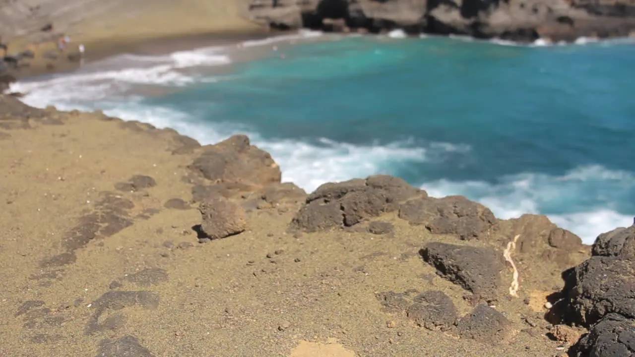 Waves Crash Against Shore behind Black Rocks on Green Sand Beach in Hawaii