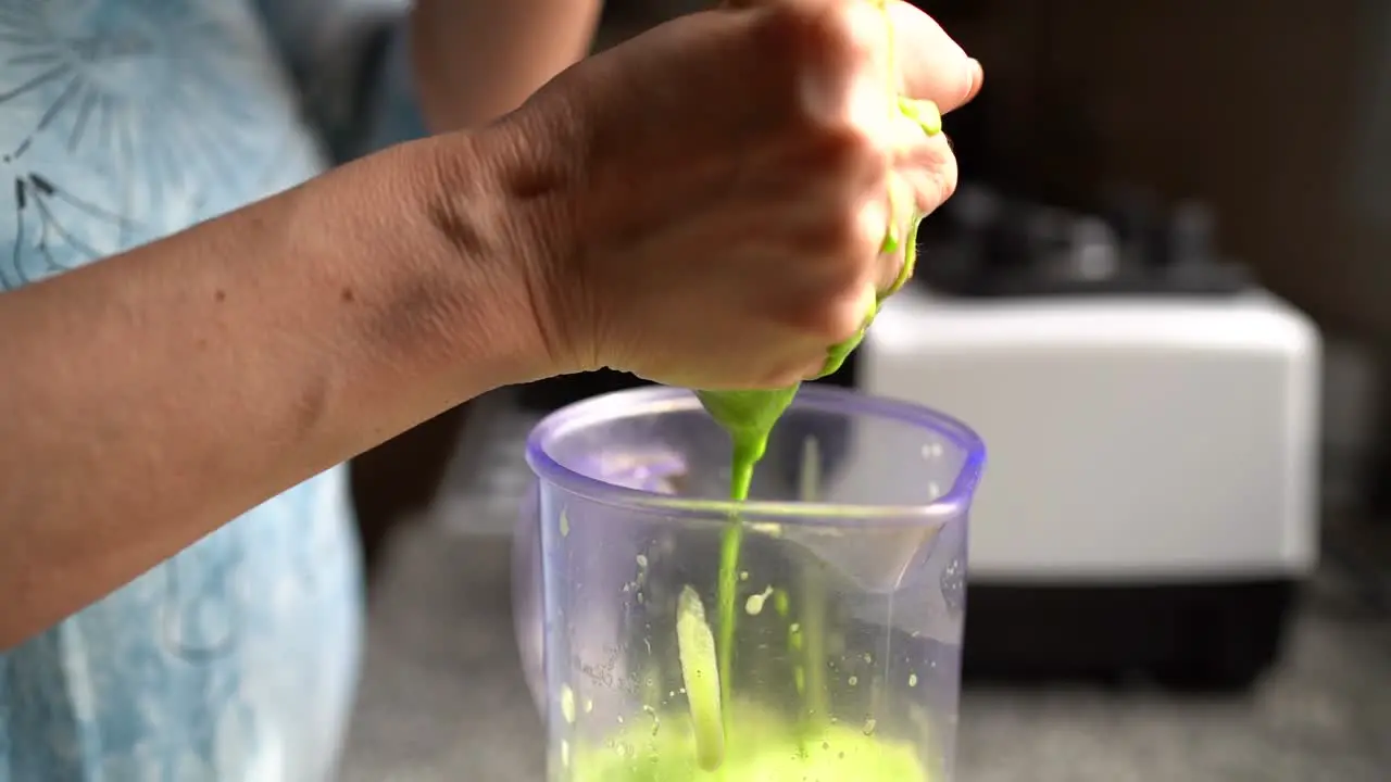 Hands Squeezing Out Green Juice In Cheese Cloth