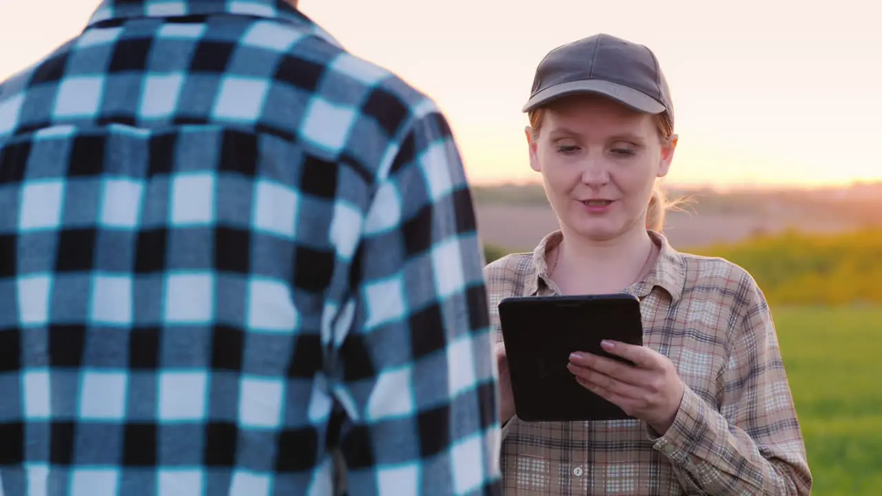 Man And Female Farmers Work In A Field At Sunset Use A Tablet 2