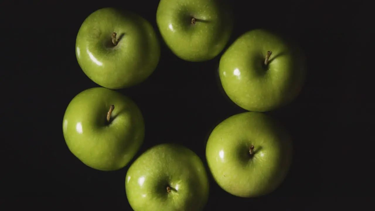 Overhead Studio Shot Of Circle Of Green Apples Revolving Against Black Background