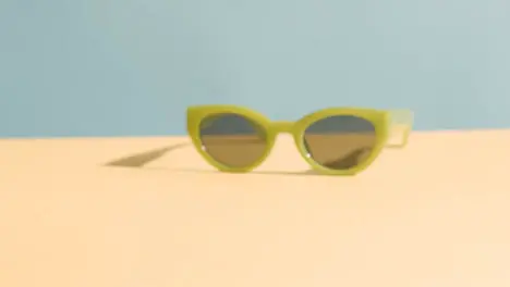 Summer Concept Of Hand Picking Up Sunglasses On Yellow Blue Background