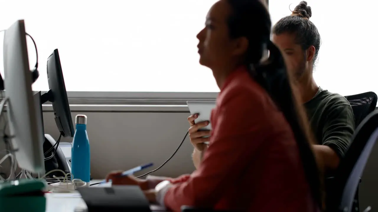 Business colleagues using digital tablet and writing on diary at desk 4k