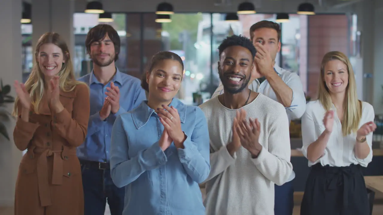 Portrait Of Applauding Multi-Cultural Business Team Standing In Modern Open Plan Office