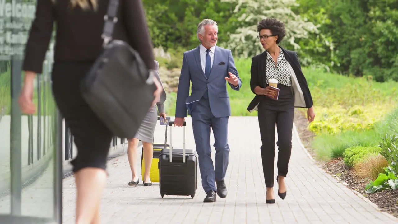 Group Of Business Delegates With Luggage Arriving At Conference Hotel