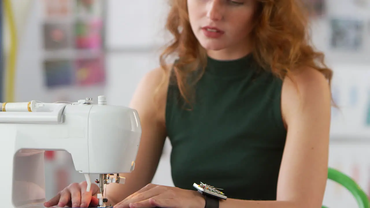 Female Student Or Business Owner Working In Fashion Industry Using Sewing Machine In Studio