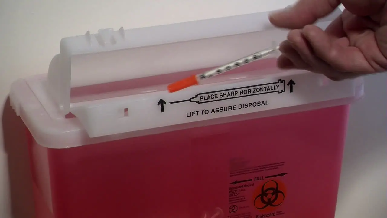 Disposing of a used syringe in a sharps container