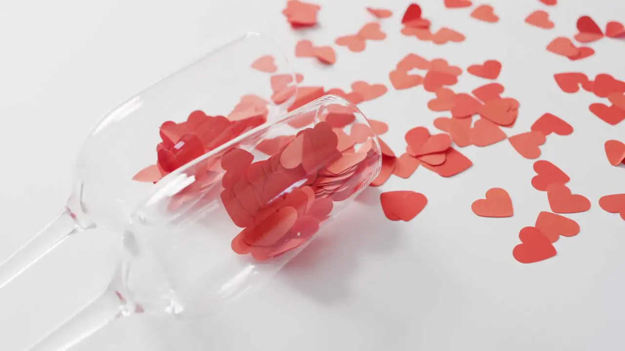 Champagne glasses with paper hearts on pink background at valentine's day