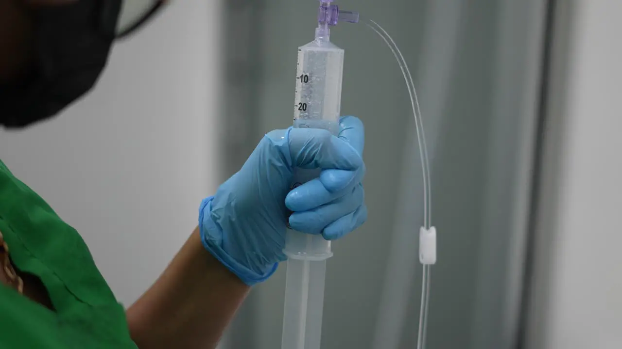 nurse administering anesthesia with syringe in hospital in operating room