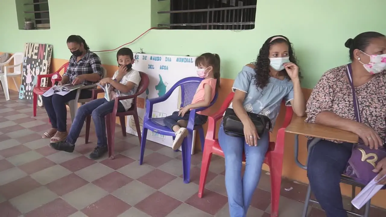 Women and children sitting waiting for a medical consultation during a health brigade in an improvised clinic in a community school in a poor area