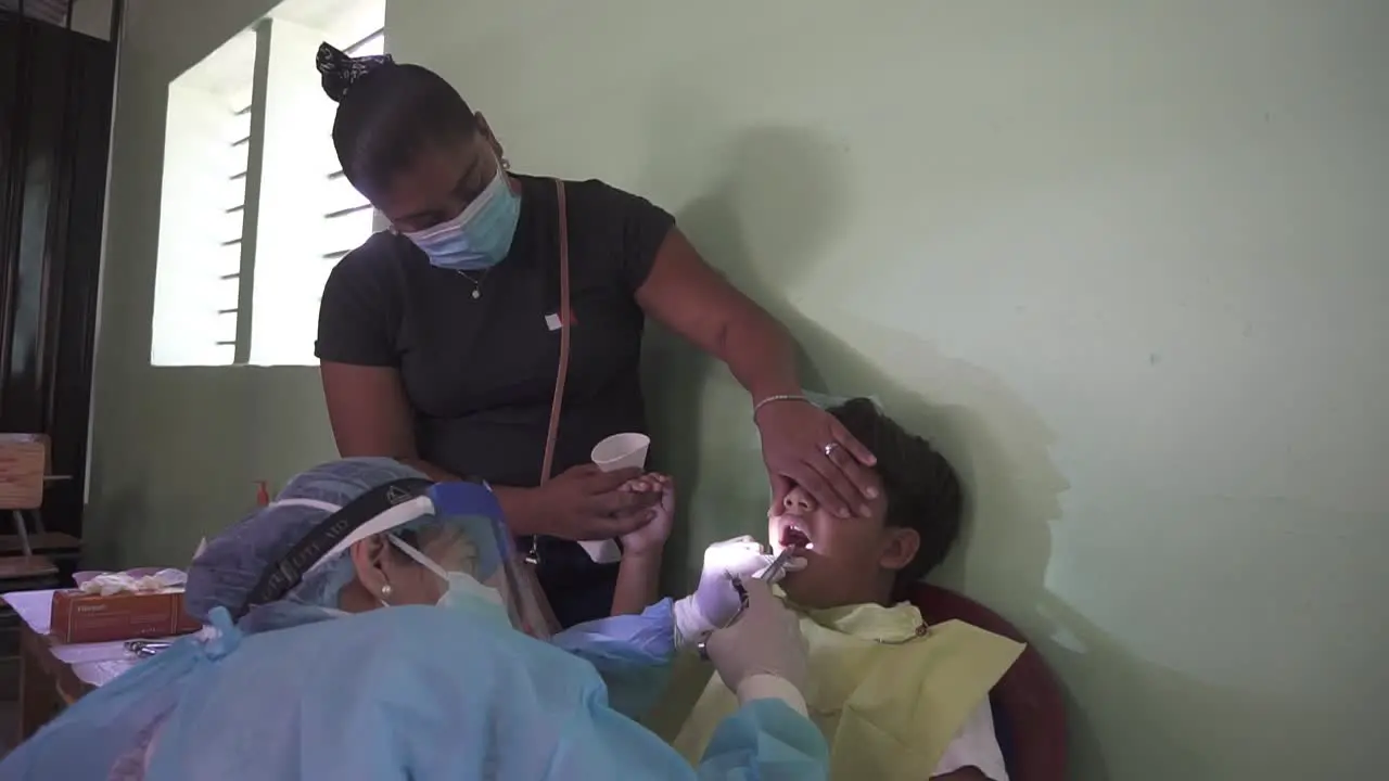 Female dentist applies anesthesia to perform a procedure on a child's teeth during mobile medical brigade