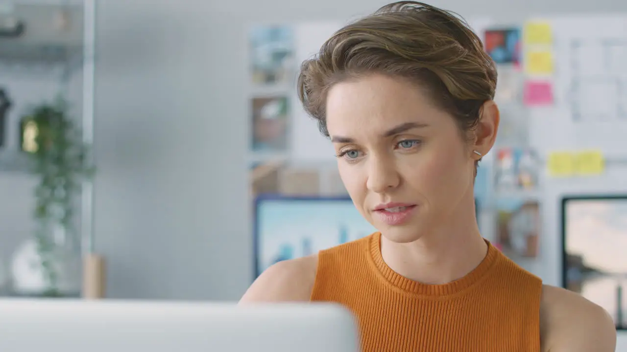 Close Up Of Smiling Female Architect In Office Working At Desk On Laptop