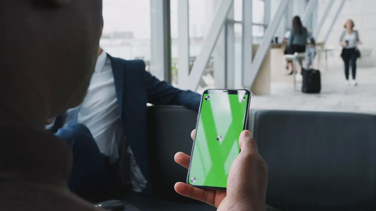 Close Up Of Businessman Sitting In Airport Departure Lounge Looking At Mobile Phone Screen