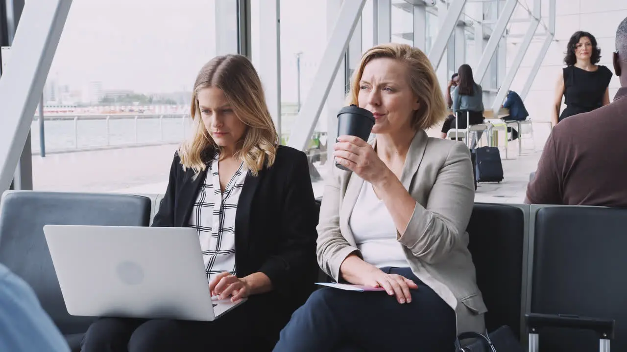 Businesswomen Sitting In Airport Departure Working On Laptop