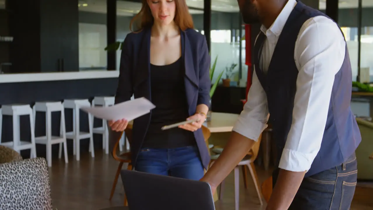 Side view of young black businessman with laptop using mobile phone in a modern office 4k