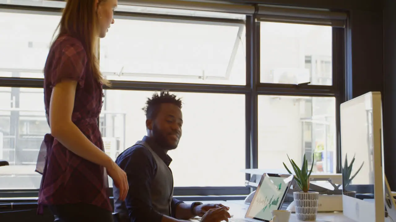 Side view of young black businessman working on laptop at desk in a modern office 4k