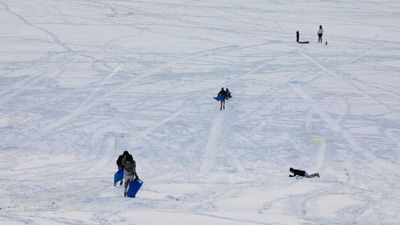 People tobogganing during the winter down a hill