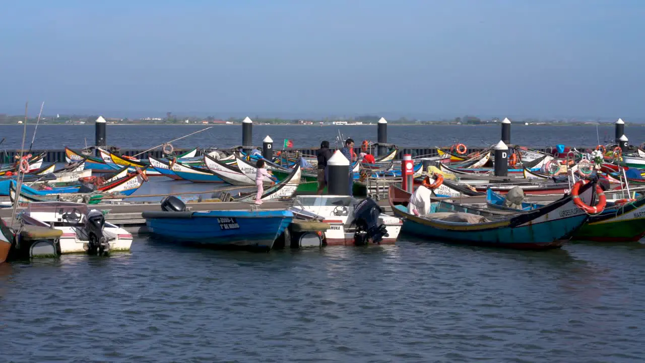 People walking fishing boats moored at pier Ria de Aveiro Torreira