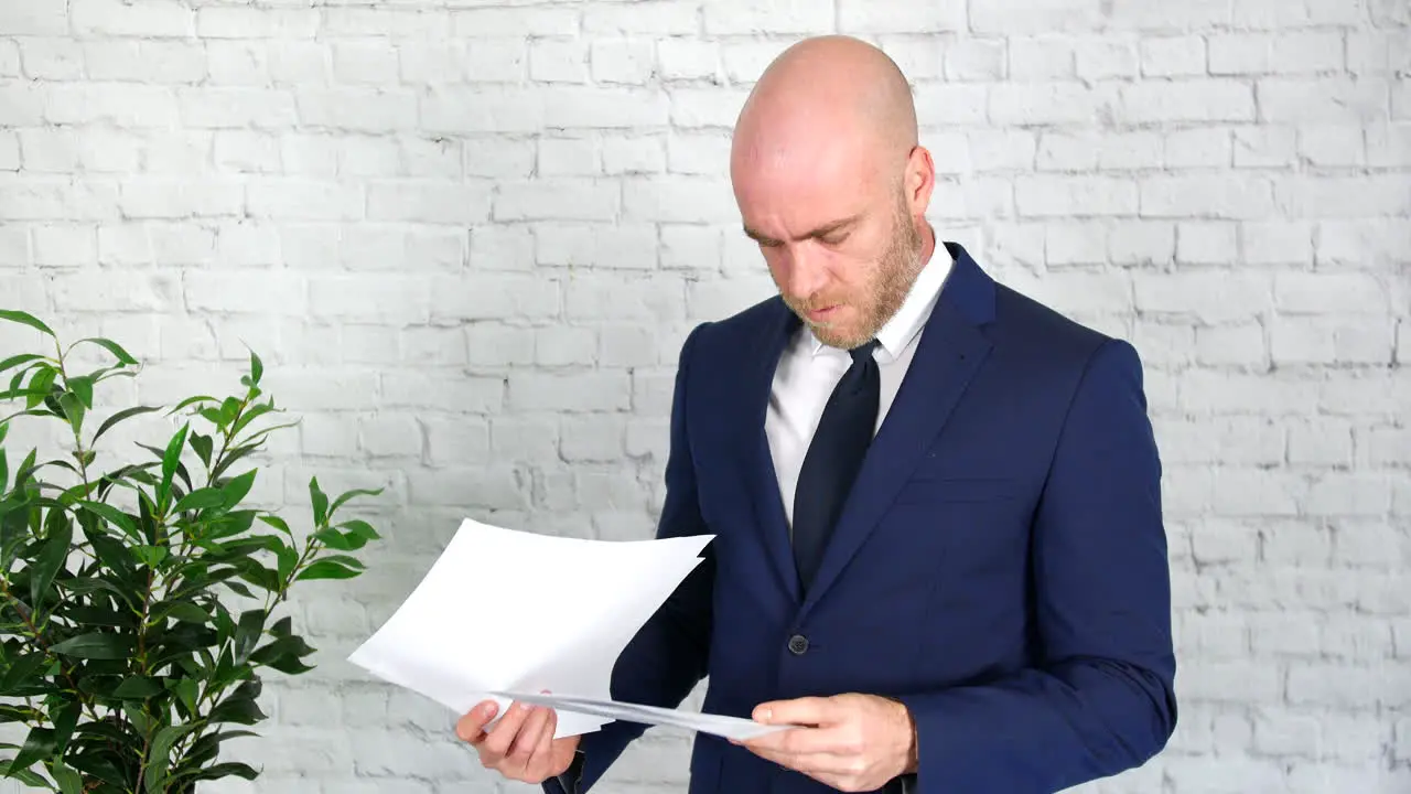 A businessman is upset after reading through papers which he then throws in the air