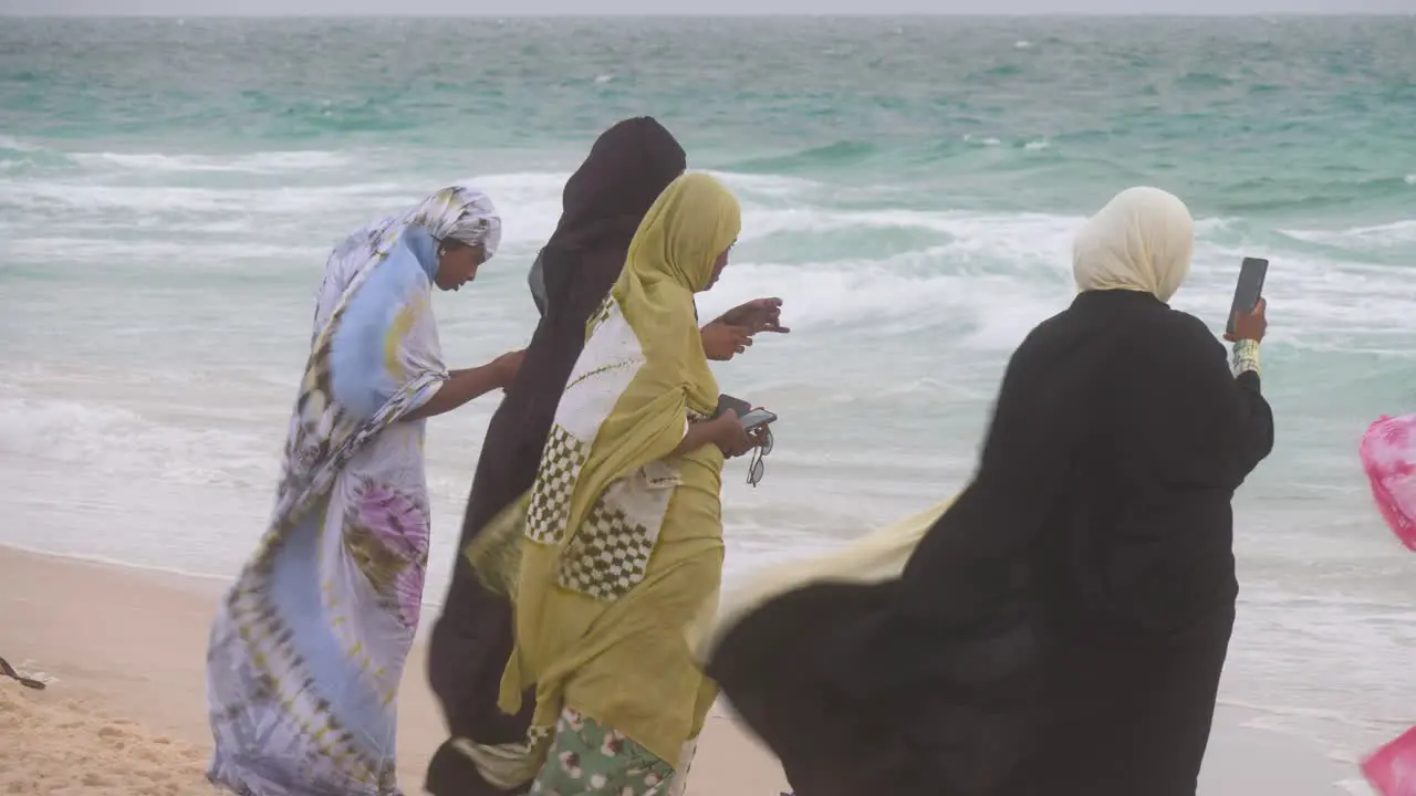 Some muslim african women enjoy the beach in a windy day