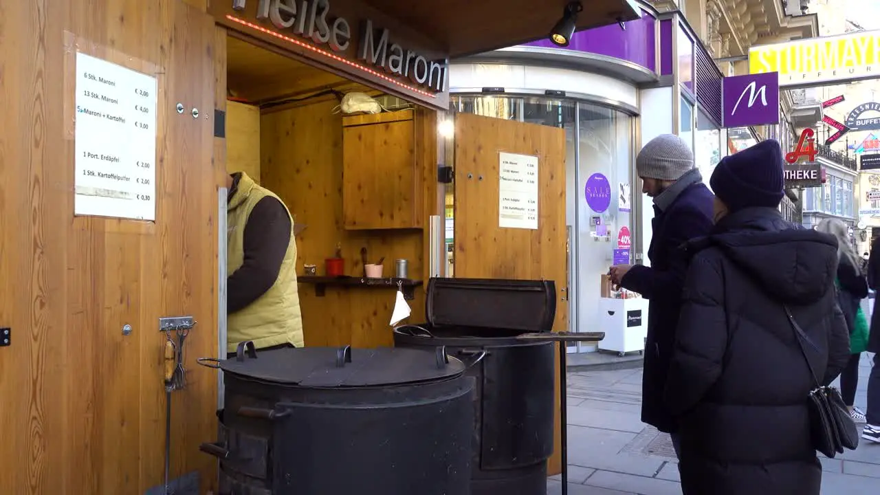 Man buying roasted chestnuts from street vendor typical winter street food