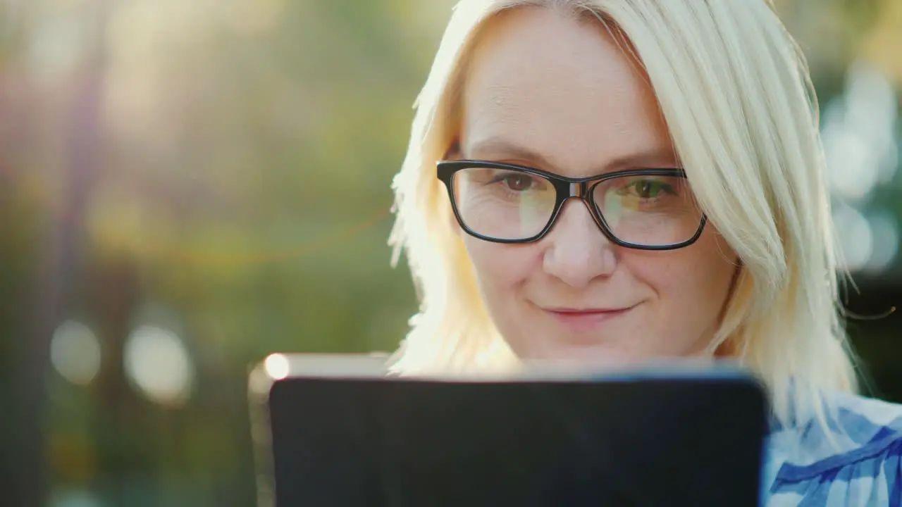 Portrait Of A Young Woman Wearing Glasses Enjoying A Tablet In The Park Beautiful Sun Glare 4k Slow 