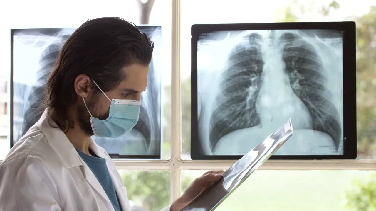 Doctor with face mask checking carefully X-ray film for treatment plan