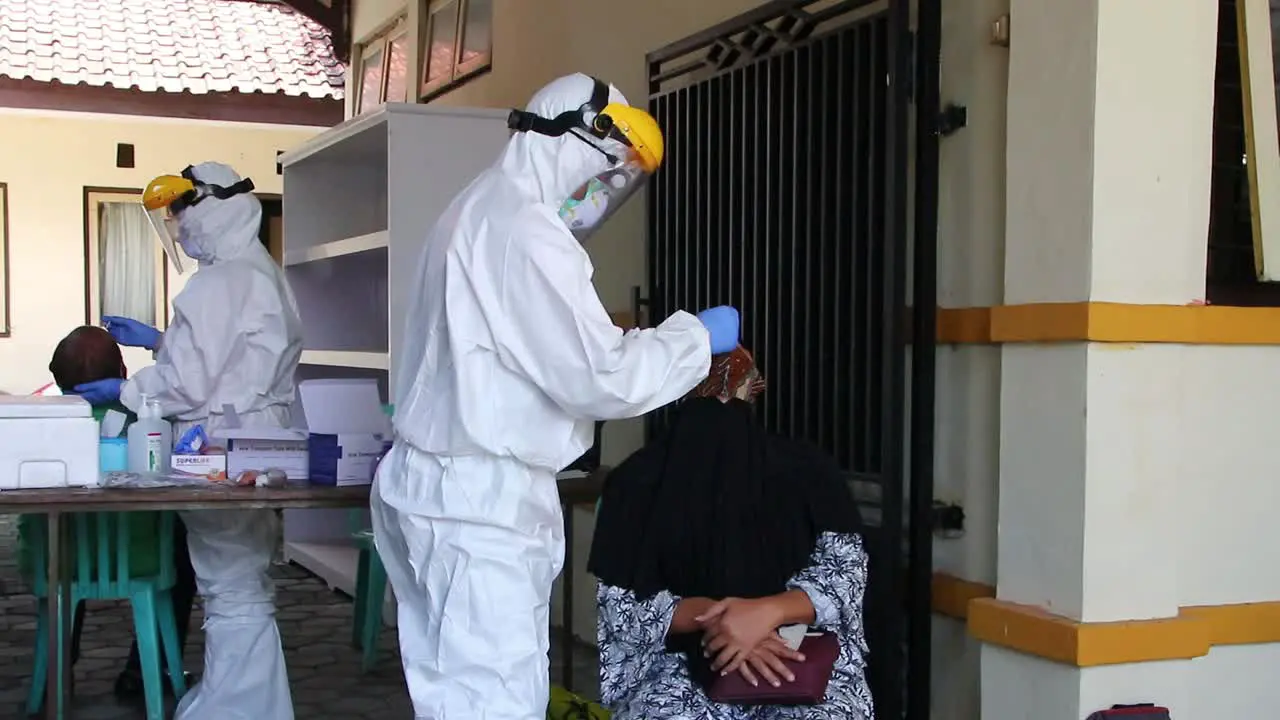 A doctor in a protective suit taking a nasal swab from a person to test for possible coronavirus infection