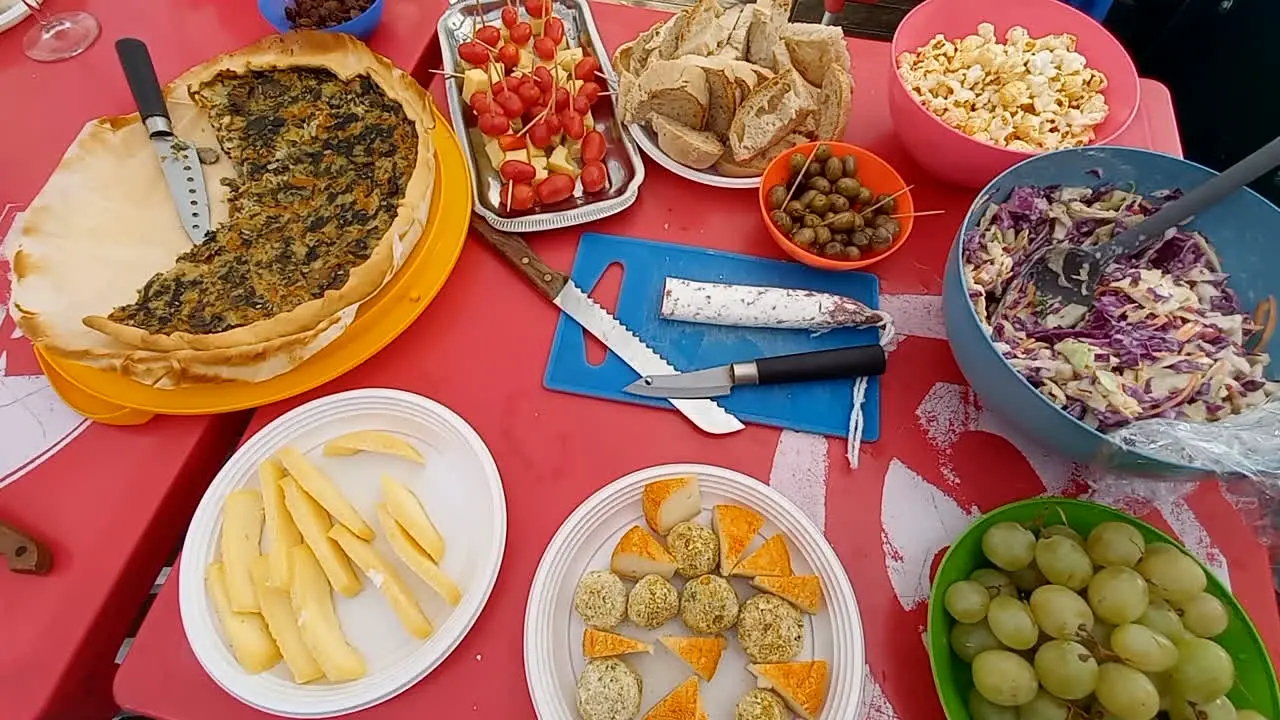 Picnic table full of food pizza cheese fruit olives bread and tomatoes