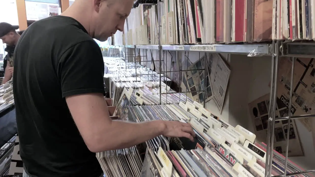 Male Looking and Browsing through Vinyl Records at a Record Store