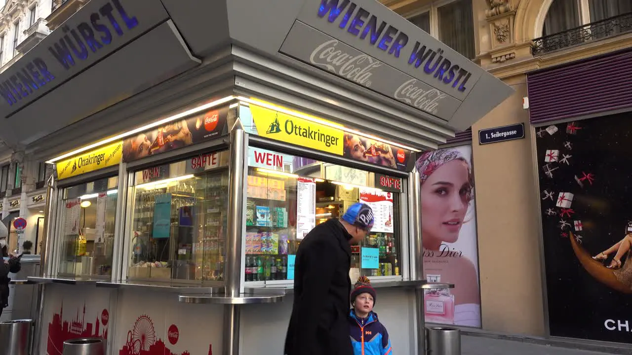 Typical Viennese sausage stand with people walking past