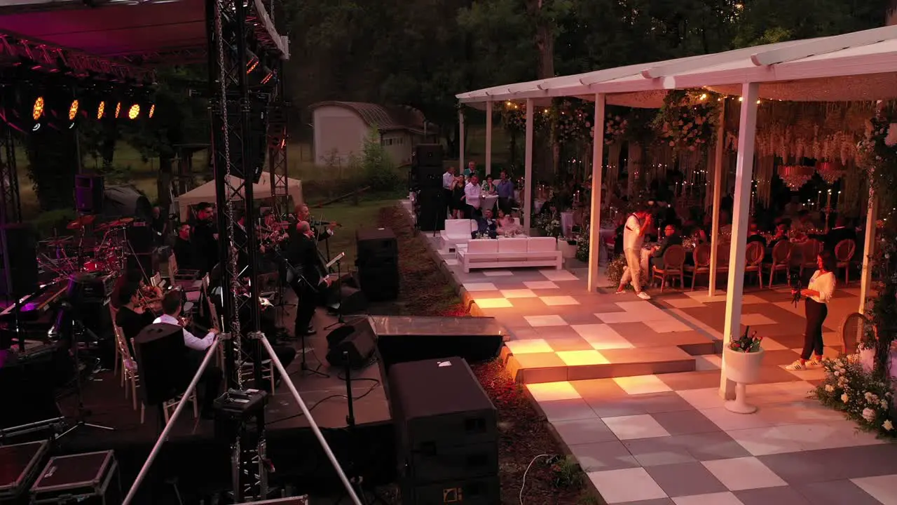 Zoom in drone shot of a orchestra playing at a wedding party