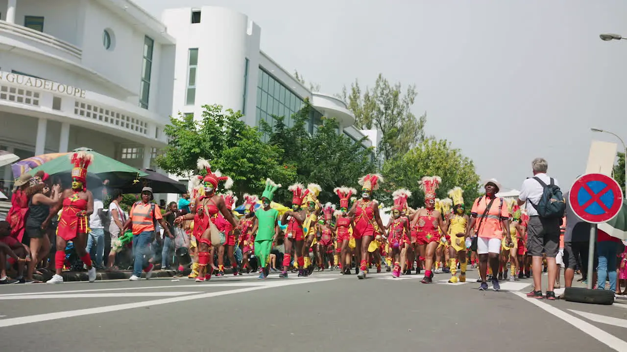 Wide slow motion of a big procession celebrating carnival in the streets of Pointe-à-Pitre in Guadeloupe