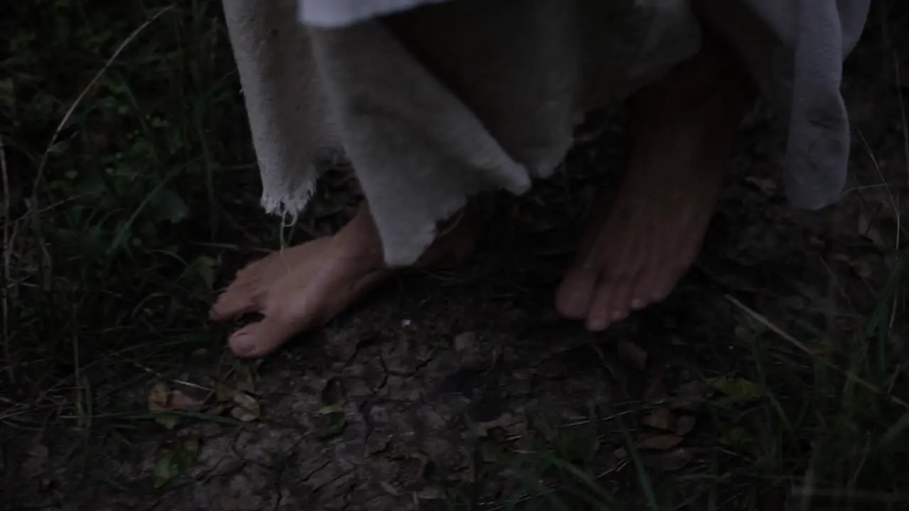 Closeup of robed mans feet or Jesus walking through forest trees