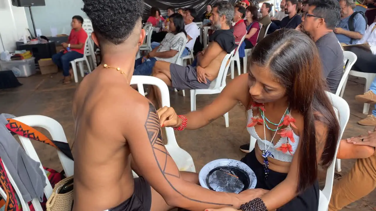 A beautiful Amazon lady applies the black traditional drawing to a man